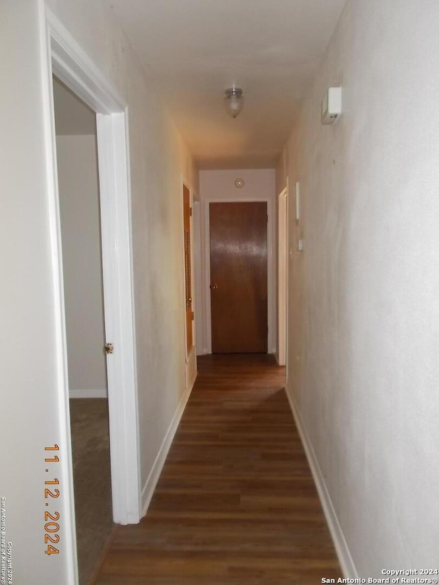 hallway featuring dark wood-style floors and baseboards