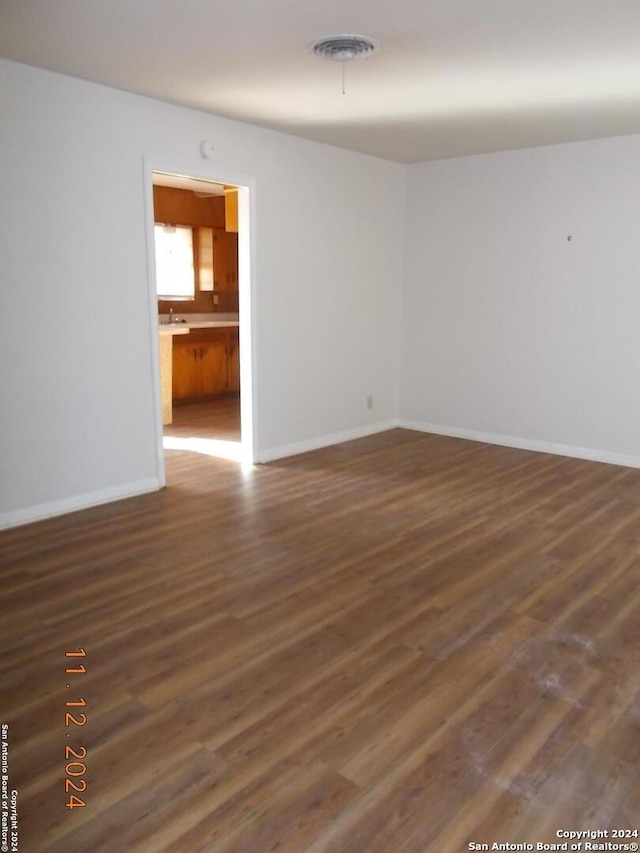 spare room featuring dark wood-style floors, visible vents, and baseboards