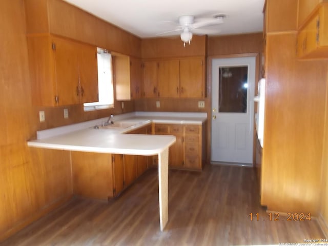 kitchen with dark wood-style flooring, brown cabinets, light countertops, a sink, and a peninsula