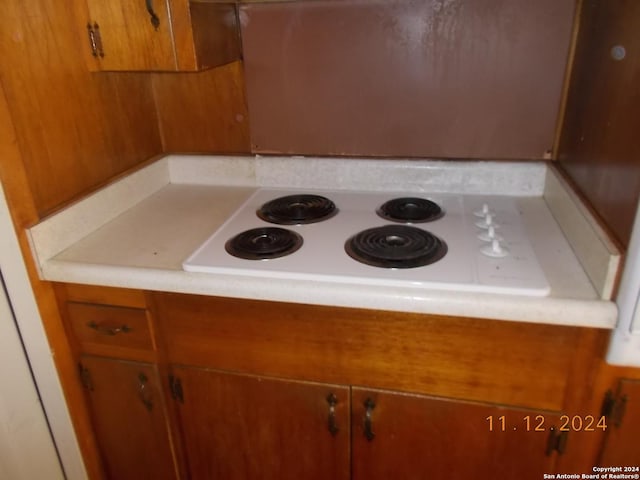 room details with brown cabinets, white electric cooktop, and light countertops