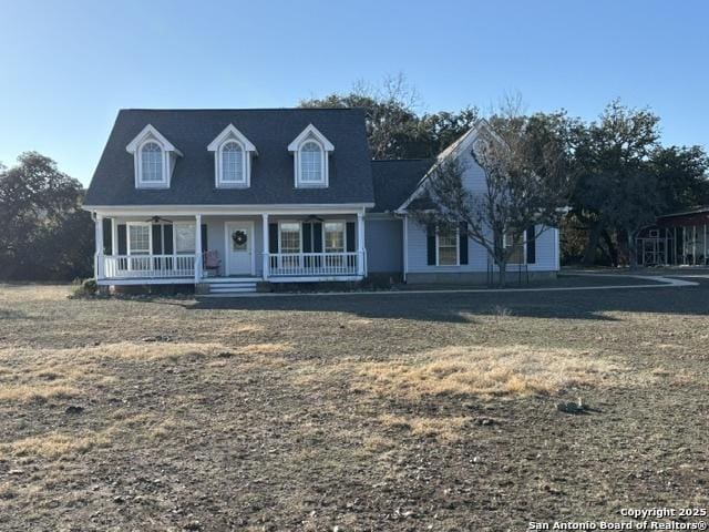 cape cod home featuring covered porch