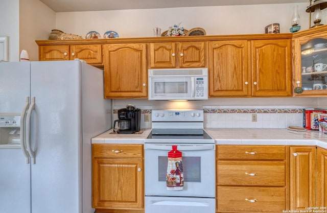 kitchen featuring white appliances, glass insert cabinets, and brown cabinets