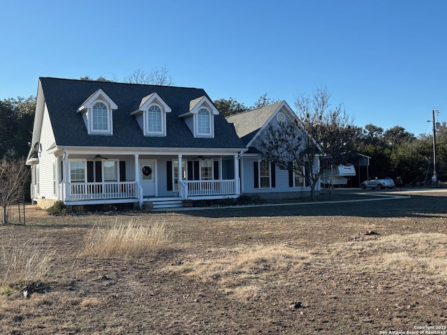 cape cod-style house featuring covered porch and a shingled roof