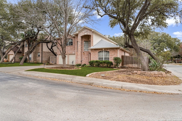 traditional-style house featuring brick siding, concrete driveway, an attached garage, fence, and a front lawn