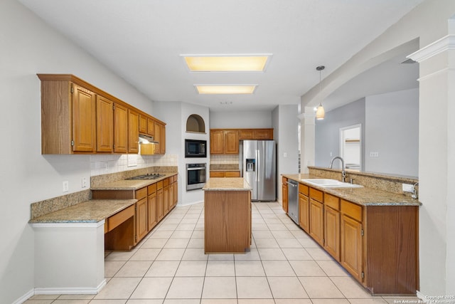 kitchen with under cabinet range hood, a sink, a kitchen island, hanging light fixtures, and appliances with stainless steel finishes