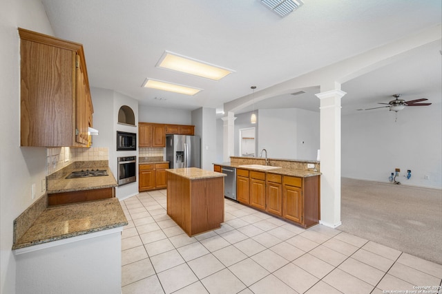 kitchen with a sink, stainless steel appliances, brown cabinetry, and a kitchen island