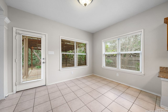 empty room featuring light tile patterned flooring and baseboards