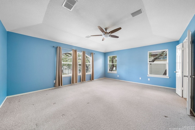 carpeted spare room with ceiling fan, vaulted ceiling, visible vents, and baseboards