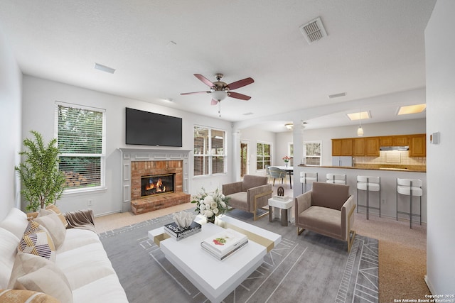 living area with a brick fireplace, visible vents, and a healthy amount of sunlight