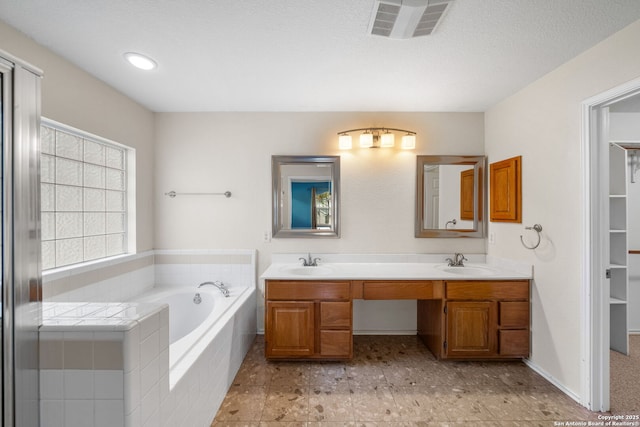 full bath featuring visible vents, a sink, a garden tub, and double vanity