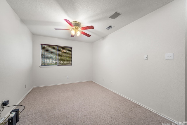 carpeted spare room featuring a ceiling fan, baseboards, visible vents, and a textured ceiling