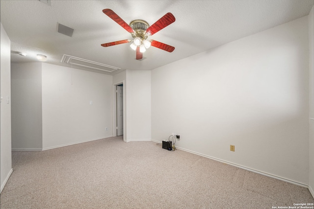 empty room with attic access, carpet flooring, a textured ceiling, and baseboards