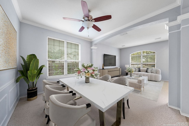 dining area with ornamental molding, a ceiling fan, decorative columns, and light colored carpet