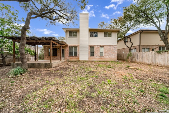 back of house featuring a fenced backyard, brick siding, a chimney, and a pergola