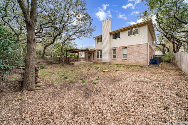 back of house featuring brick siding, a chimney, cooling unit, and a fenced backyard