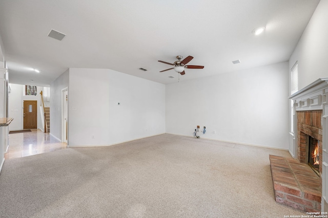 unfurnished living room with ceiling fan, light carpet, a fireplace, visible vents, and baseboards