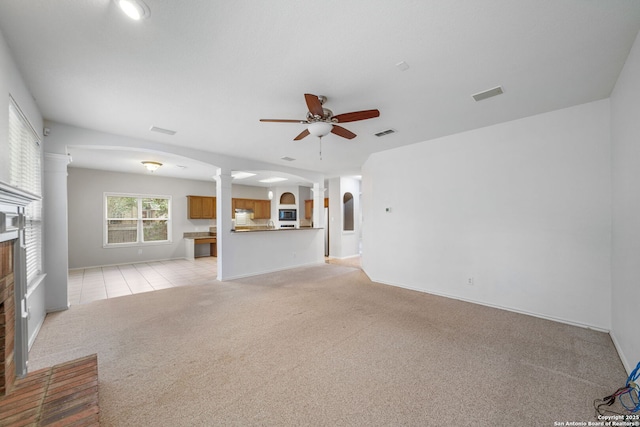 unfurnished living room with visible vents, arched walkways, a ceiling fan, light colored carpet, and a fireplace