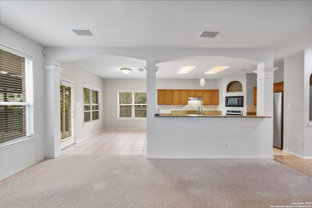 kitchen featuring a peninsula, ornate columns, and black microwave