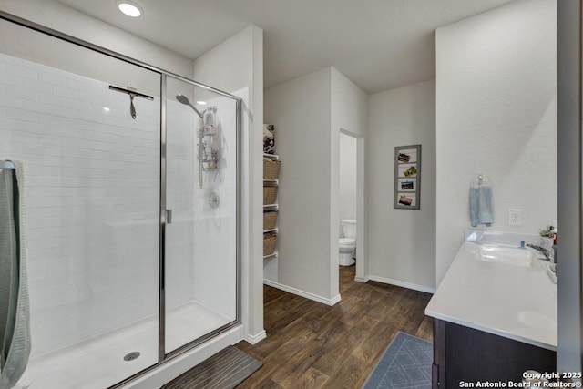 full bath featuring a stall shower, baseboards, toilet, wood finished floors, and vanity