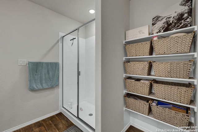 bathroom featuring a stall shower, baseboards, and wood finished floors