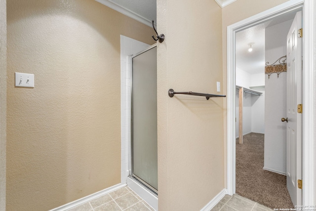 bathroom with ornamental molding, a stall shower, tile patterned flooring, and a textured wall