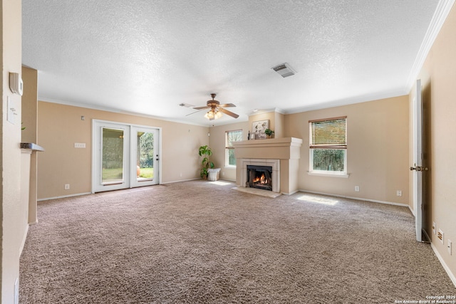 unfurnished living room with a warm lit fireplace, light carpet, visible vents, baseboards, and ornamental molding