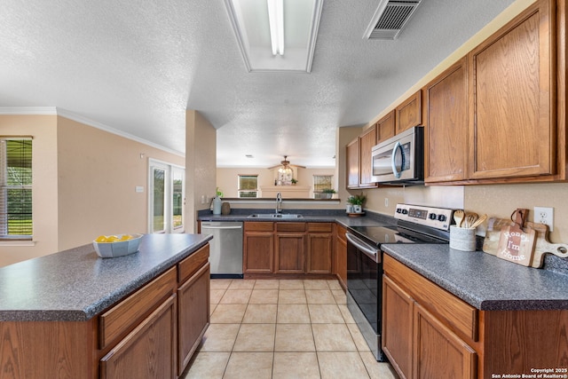 kitchen with brown cabinets, dark countertops, visible vents, appliances with stainless steel finishes, and a sink