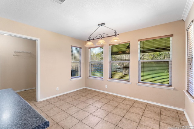 unfurnished dining area featuring baseboards, a textured ceiling, and light tile patterned flooring