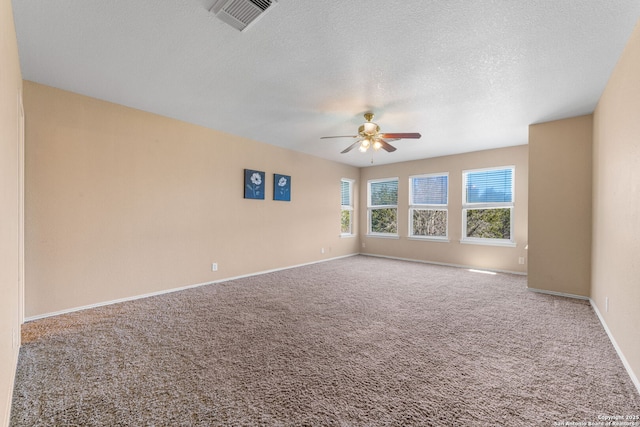 empty room with carpet floors, visible vents, ceiling fan, and a textured ceiling