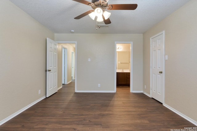 unfurnished bedroom with baseboards, visible vents, connected bathroom, dark wood-type flooring, and a textured ceiling