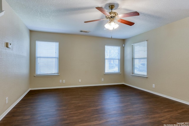 spare room with a ceiling fan, visible vents, a textured ceiling, and wood finished floors