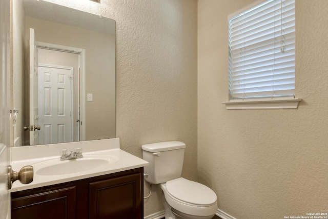 bathroom with toilet, a textured wall, and vanity