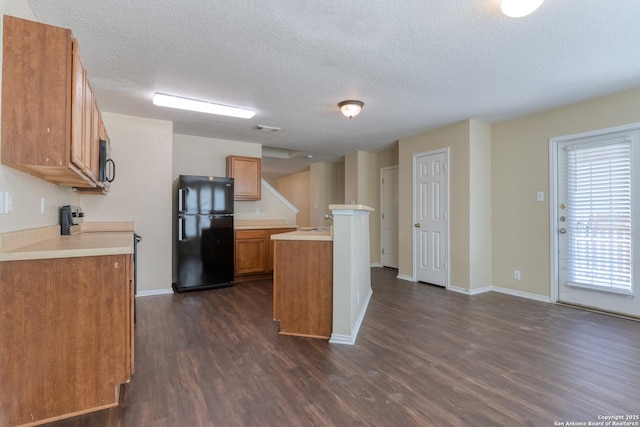 kitchen with black appliances, dark wood-type flooring, light countertops, and brown cabinets