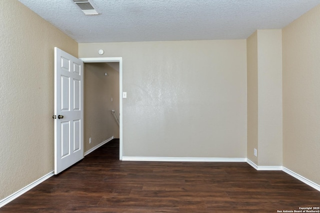 unfurnished room with visible vents, a textured wall, a textured ceiling, wood finished floors, and baseboards