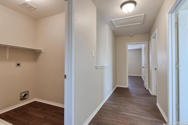 hallway featuring attic access, a textured ceiling, visible vents, and dark wood-style flooring