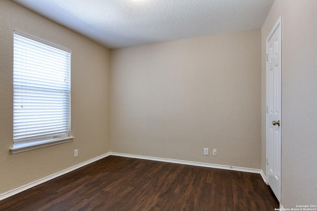 empty room with baseboards, dark wood finished floors, and a textured ceiling