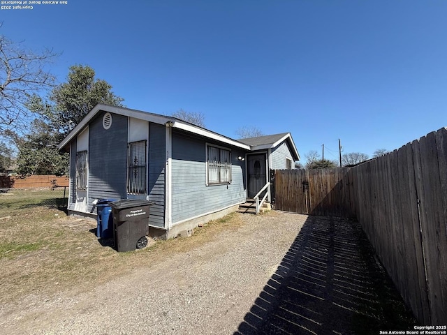 view of side of home featuring entry steps and fence