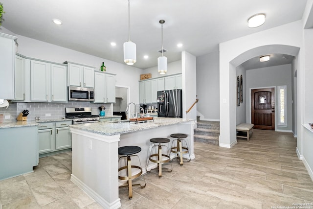 13818 Cessna, San Antonio, TX 78245 - kitchen featuring stainless steel appliances, backsplash, a center island with sink, light stone countertops, and decorative light fixtures