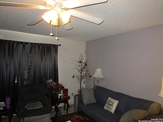 living room featuring ceiling fan and a textured ceiling