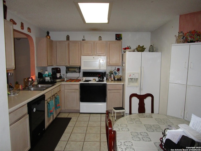 kitchen with white appliances, light tile patterned floors, light brown cabinets, a sink, and light countertops