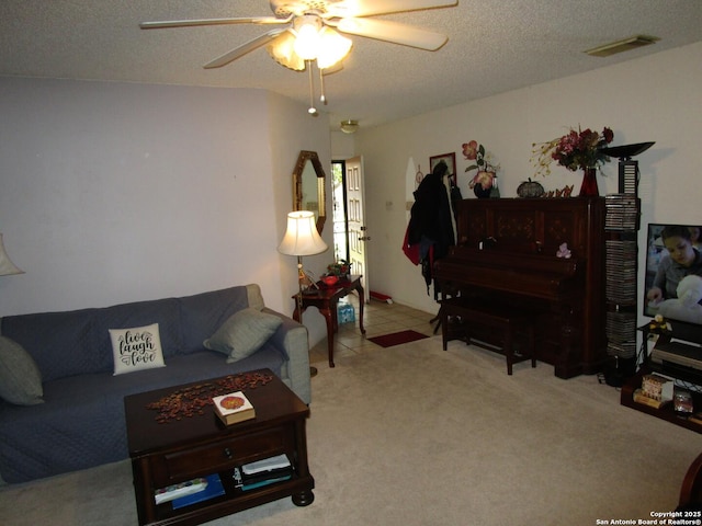 living area with light carpet, visible vents, ceiling fan, a textured ceiling, and light tile patterned flooring