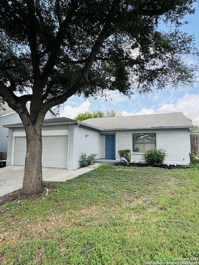 single story home with a front yard, concrete driveway, brick siding, and an attached garage