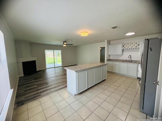 kitchen with open floor plan, freestanding refrigerator, white cabinetry, and a center island