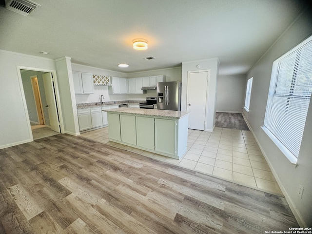 kitchen with a center island, stainless steel appliances, visible vents, white cabinets, and a sink