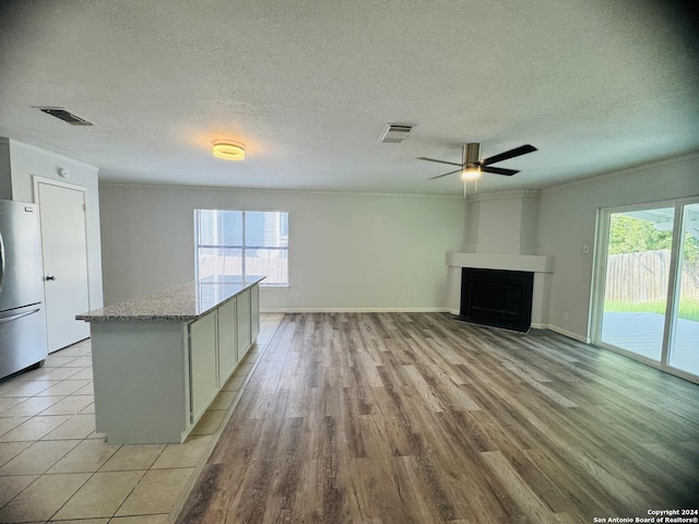 kitchen with freestanding refrigerator, visible vents, a fireplace, and white cabinetry