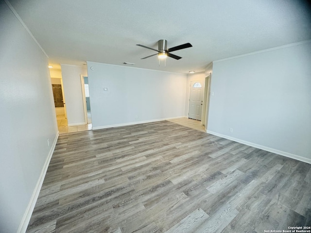 empty room with baseboards, light wood-style flooring, ornamental molding, and a ceiling fan