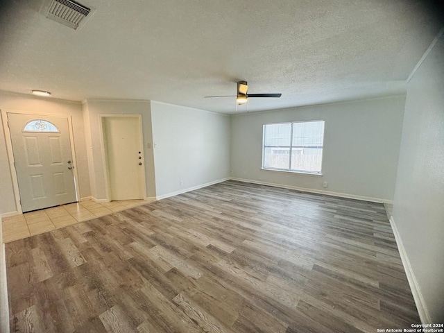 interior space featuring light wood-type flooring, visible vents, ceiling fan, and a textured ceiling