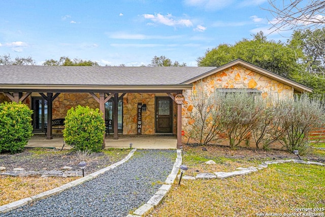 ranch-style house featuring stone siding and a shingled roof