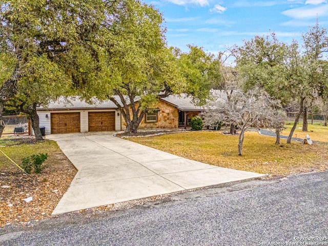 view of front of house with concrete driveway, a front lawn, an attached garage, and fence