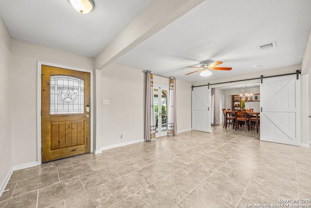 foyer featuring visible vents, ceiling fan, baseboards, and a barn door